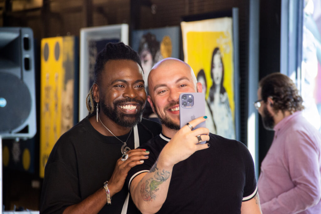 Dois homens, um branco e outro negro tirando selfie no evento